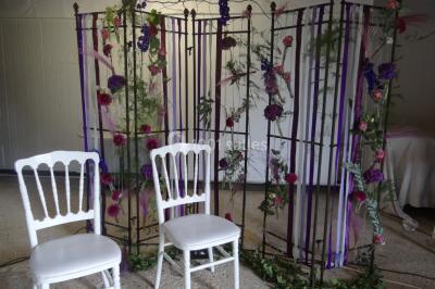 Lit simple avec couvre-lit fleuri dans une chambre lumineuse, éclairée par une lampe de chevet près d'une fenêtre.