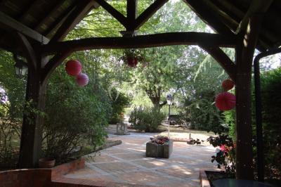 Lit simple avec couvre-lit fleuri dans une chambre lumineuse, éclairée par une lampe de chevet près d'une fenêtre.