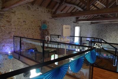 Lit simple avec couvre-lit fleuri dans une chambre lumineuse, éclairée par une lampe de chevet près d'une fenêtre.