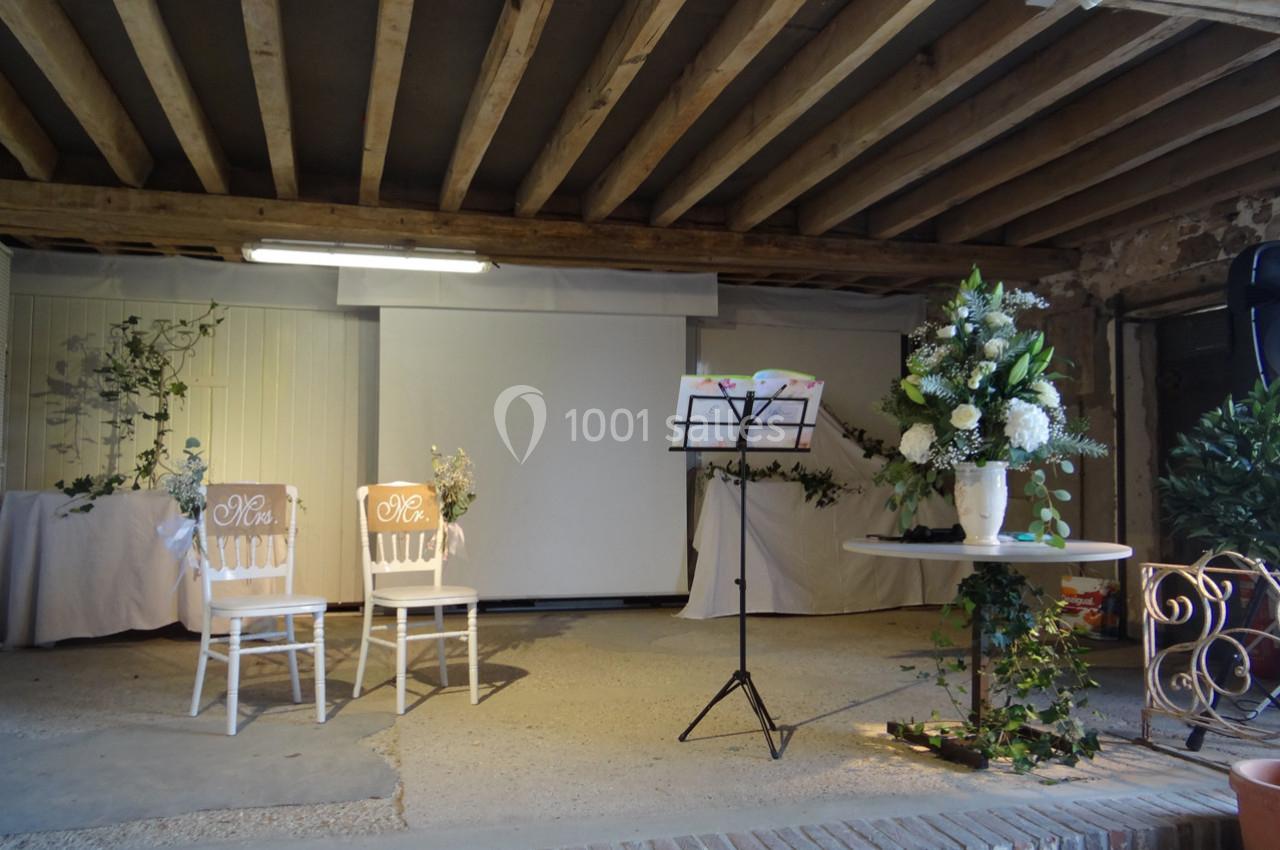 Deux chaises décorées, un pupitre et des arrangements floraux dans une salle avec poutres apparentes.