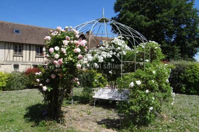 Lit simple avec couvre-lit fleuri dans une chambre lumineuse, éclairée par une lampe de chevet près d'une fenêtre.