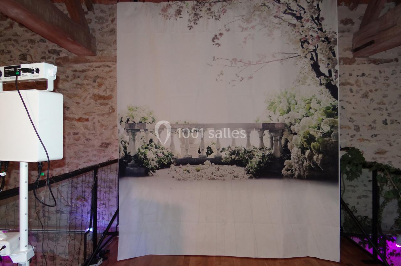 Rideau imprimé représentant une balustrade entourée de végétation, installé dans une pièce avec poutres apparentes.