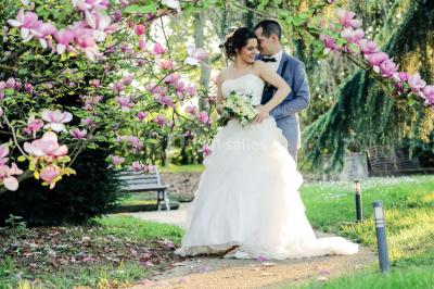 Lit simple avec couvre-lit fleuri dans une chambre lumineuse, éclairée par une lampe de chevet près d'une fenêtre.