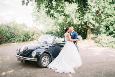 Lit simple avec couvre-lit fleuri dans une chambre lumineuse, éclairée par une lampe de chevet près d'une fenêtre.