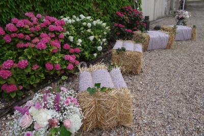 Lit simple avec couvre-lit fleuri dans une chambre lumineuse, éclairée par une lampe de chevet près d'une fenêtre.