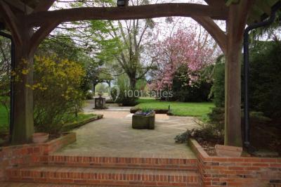 Lit simple avec couvre-lit fleuri dans une chambre lumineuse, éclairée par une lampe de chevet près d'une fenêtre.