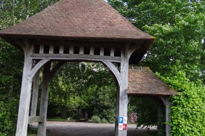 Lit simple avec couvre-lit fleuri dans une chambre lumineuse, éclairée par une lampe de chevet près d'une fenêtre.