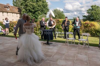 Lit simple avec couvre-lit fleuri dans une chambre lumineuse, éclairée par une lampe de chevet près d'une fenêtre.