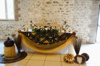 Lit simple avec couvre-lit fleuri dans une chambre lumineuse, éclairée par une lampe de chevet près d'une fenêtre.