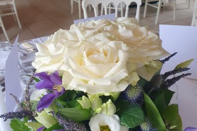 Lit simple avec couvre-lit fleuri dans une chambre lumineuse, éclairée par une lampe de chevet près d'une fenêtre.