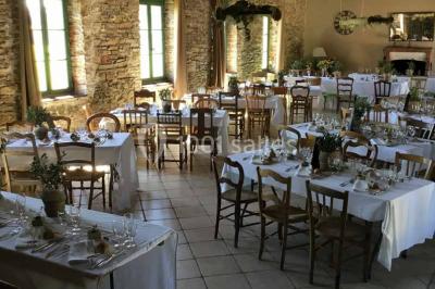 Cour extérieure éclairée en soirée, avec un grand arbre central, des tables, des palettes en bois et des invités debout.