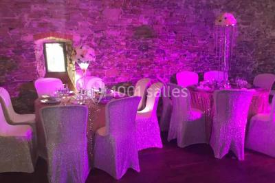 Cour extérieure éclairée en soirée, avec un grand arbre central, des tables, des palettes en bois et des invités debout.