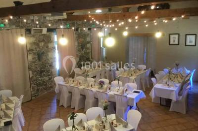 Cour extérieure éclairée en soirée, avec un grand arbre central, des tables, des palettes en bois et des invités debout.