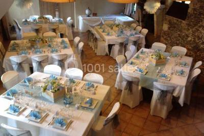 Cour extérieure éclairée en soirée, avec un grand arbre central, des tables, des palettes en bois et des invités debout.