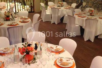 Cour extérieure éclairée en soirée, avec un grand arbre central, des tables, des palettes en bois et des invités debout.