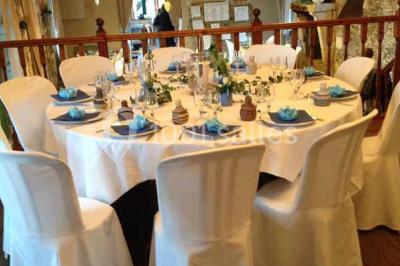 Cour extérieure éclairée en soirée, avec un grand arbre central, des tables, des palettes en bois et des invités debout.