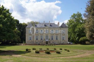Cour extérieure éclairée en soirée, avec un grand arbre central, des tables, des palettes en bois et des invités debout.