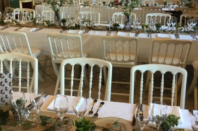 Un groupe de personnes rassemblées sous de grands arbres devant des bâtiments en pierre par une journée ensoleillée.