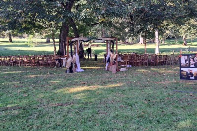 Un groupe de personnes rassemblées sous de grands arbres devant des bâtiments en pierre par une journée ensoleillée.