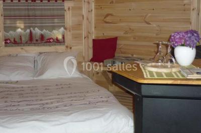 Cabane en bois perchée dans les arbres avec une passerelle en bois, entourée de végétation automnale et deux vélos au…