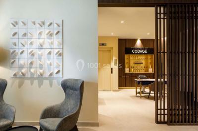 Piscine intérieure avec chaises longues rayées, éclairage doux et grande fenêtre ronde donnant sur l'extérieur.