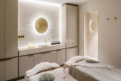 Piscine intérieure avec chaises longues rayées, éclairage doux et grande fenêtre ronde donnant sur l'extérieur.