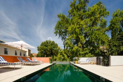 Piscine intérieure avec chaises longues rayées, éclairage doux et grande fenêtre ronde donnant sur l'extérieur.
