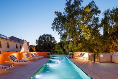 Piscine intérieure avec chaises longues rayées, éclairage doux et grande fenêtre ronde donnant sur l'extérieur.