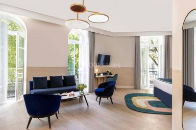 Piscine intérieure avec chaises longues rayées, éclairage doux et grande fenêtre ronde donnant sur l'extérieur.