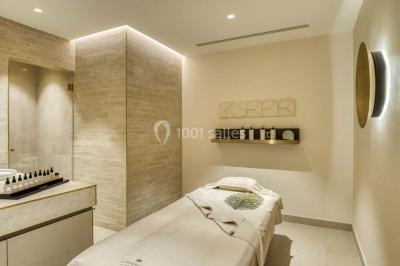 Piscine intérieure avec chaises longues rayées, éclairage doux et grande fenêtre ronde donnant sur l'extérieur.