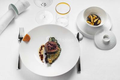 Piscine intérieure avec chaises longues rayées, éclairage doux et grande fenêtre ronde donnant sur l'extérieur.