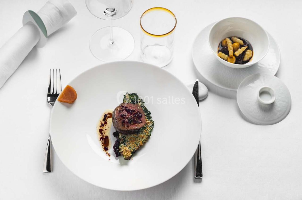Assiette gastronomique avec viande, légumes verts, sauce au vinaigre balsamique et noix dans un bol à côté.