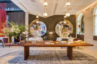 Piscine intérieure avec chaises longues rayées, éclairage doux et grande fenêtre ronde donnant sur l'extérieur.