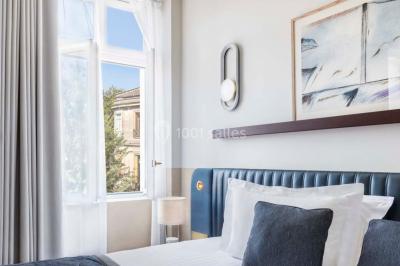 Piscine intérieure avec chaises longues rayées, éclairage doux et grande fenêtre ronde donnant sur l'extérieur.