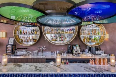 Piscine intérieure avec chaises longues rayées, éclairage doux et grande fenêtre ronde donnant sur l'extérieur.