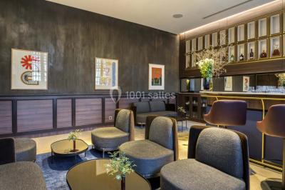 Piscine intérieure avec chaises longues rayées, éclairage doux et grande fenêtre ronde donnant sur l'extérieur.