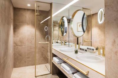 Piscine intérieure avec chaises longues rayées, éclairage doux et grande fenêtre ronde donnant sur l'extérieur.