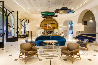 Piscine intérieure avec chaises longues rayées, éclairage doux et grande fenêtre ronde donnant sur l'extérieur.