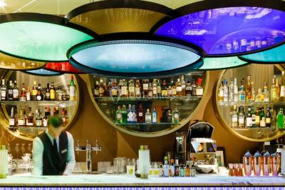 Piscine intérieure avec chaises longues rayées, éclairage doux et grande fenêtre ronde donnant sur l'extérieur.