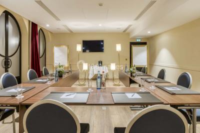 Piscine intérieure avec chaises longues rayées, éclairage doux et grande fenêtre ronde donnant sur l'extérieur.