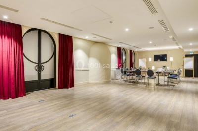 Piscine intérieure avec chaises longues rayées, éclairage doux et grande fenêtre ronde donnant sur l'extérieur.