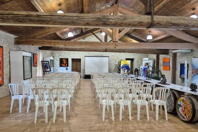 Salle avec des participants assis face à une présentation, entourée de drapeaux publicitaires et d'éléments décoratifs.