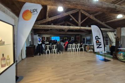 Salle avec des participants assis face à une présentation, entourée de drapeaux publicitaires et d'éléments décoratifs.