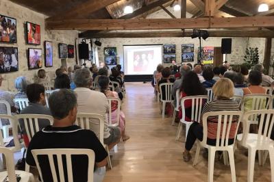 Salle avec des participants assis face à une présentation, entourée de drapeaux publicitaires et d'éléments décoratifs.