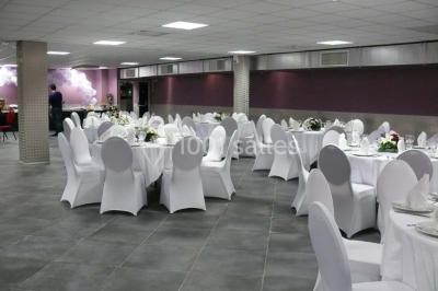 Salle vide avec un sol en carrelage gris foncé, des murs clairs et des portes rouges visibles en arrière-plan.