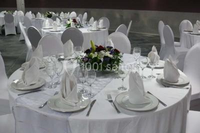 Salle vide avec un sol en carrelage gris foncé, des murs clairs et des portes rouges visibles en arrière-plan.