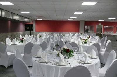 Salle vide avec un sol en carrelage gris foncé, des murs clairs et des portes rouges visibles en arrière-plan.