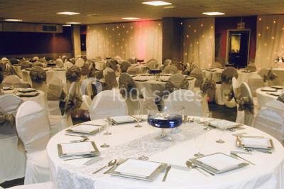 Salle vide avec un sol en carrelage gris foncé, des murs clairs et des portes rouges visibles en arrière-plan.