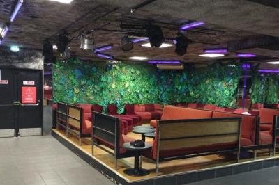 Salle vide avec un sol en carrelage gris foncé, des murs clairs et des portes rouges visibles en arrière-plan.