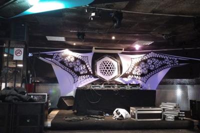 Salle vide avec un sol en carrelage gris foncé, des murs clairs et des portes rouges visibles en arrière-plan.